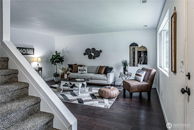 living area with stairs, dark wood-style flooring, a textured ceiling, and baseboards