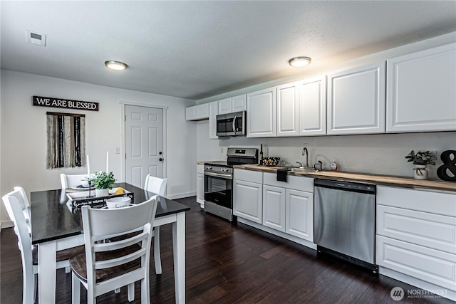 kitchen with stainless steel appliances, dark wood-style flooring, and white cabinetry