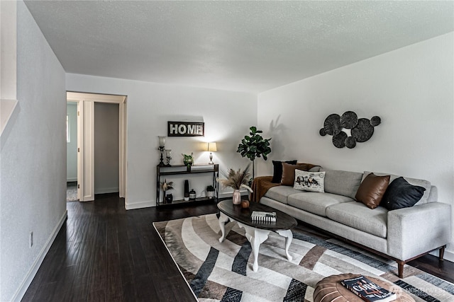 living room with dark wood-style flooring, a textured ceiling, and baseboards