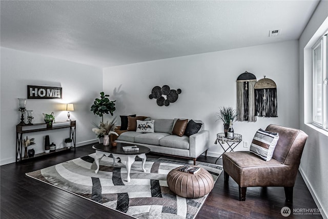 living area featuring visible vents, a textured ceiling, baseboards, and wood finished floors