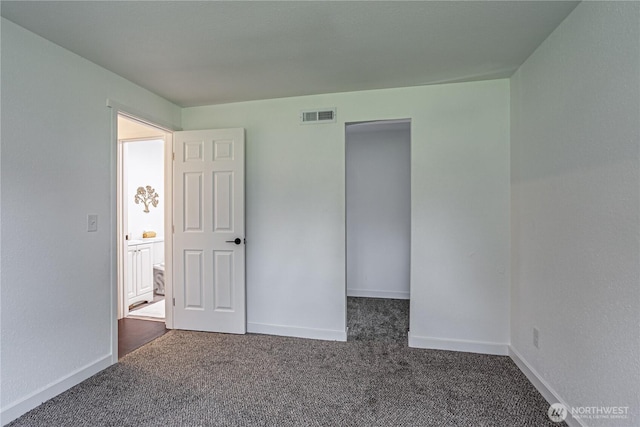 unfurnished bedroom with visible vents, dark carpet, and baseboards