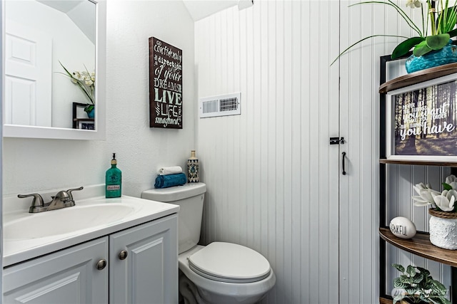 bathroom with toilet, vanity, and visible vents