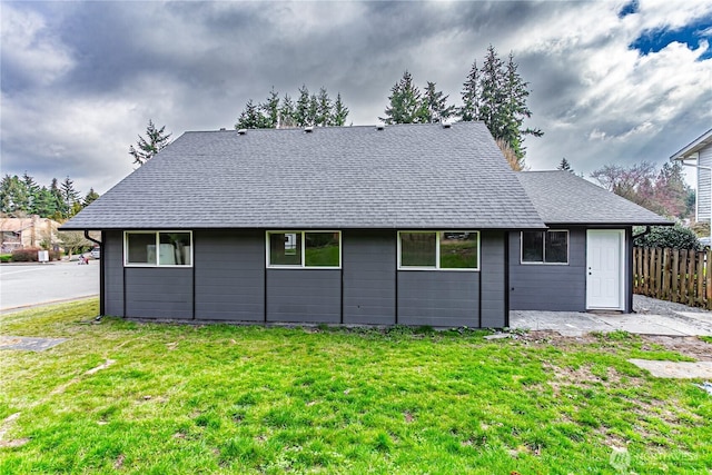 back of property with a patio area, fence, a lawn, and roof with shingles