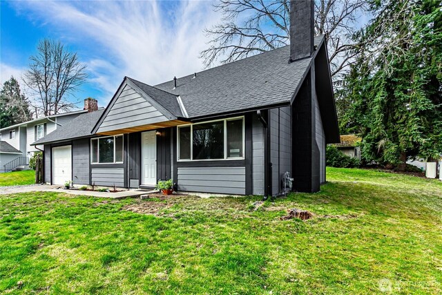 view of front of home featuring a garage, a chimney, a front lawn, and concrete driveway