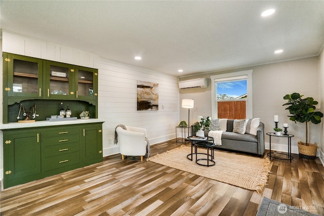 living room with recessed lighting, baseboards, light wood-style floors, and a wall mounted AC