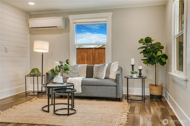 living room with baseboards, an AC wall unit, and wood finished floors