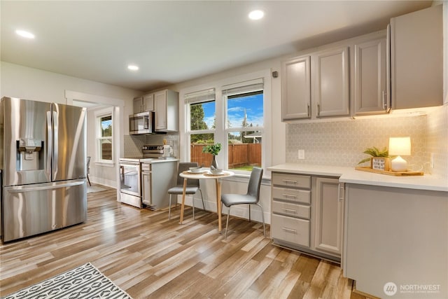 kitchen featuring light countertops, decorative backsplash, recessed lighting, light wood-style floors, and stainless steel appliances