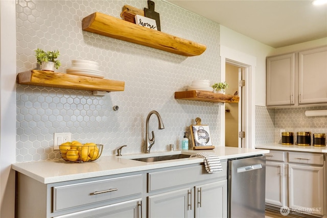 kitchen featuring a sink, dishwasher, light countertops, and open shelves