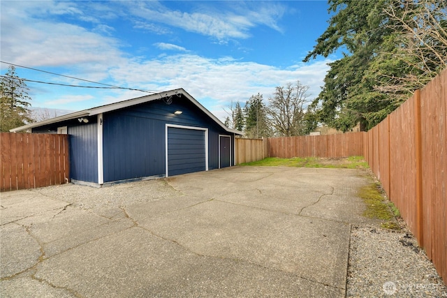 detached garage with concrete driveway and fence