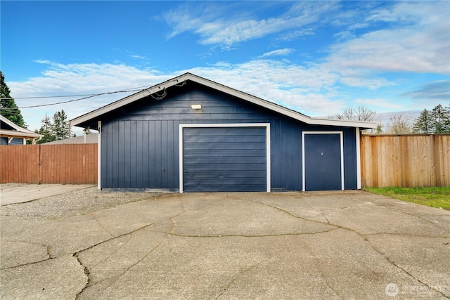 detached garage featuring driveway and fence