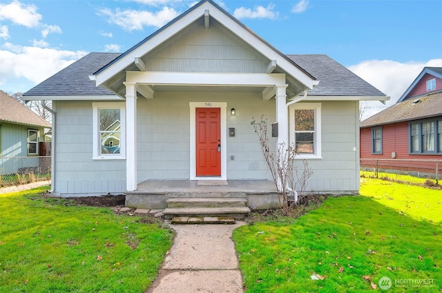 bungalow-style house featuring a shingled roof, a front yard, and fence