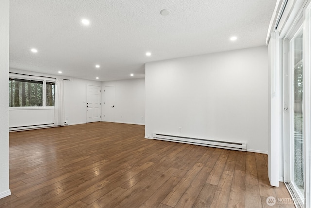 empty room featuring a baseboard heating unit, wood-type flooring, and recessed lighting