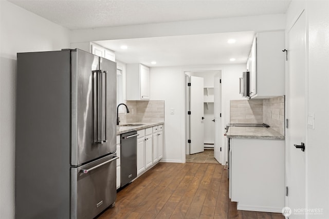 kitchen with tasteful backsplash, white cabinets, dark wood-style floors, stainless steel appliances, and a sink