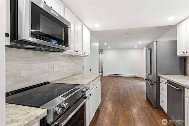 kitchen featuring appliances with stainless steel finishes, dark wood-style flooring, baseboard heating, white cabinetry, and backsplash