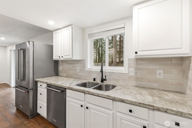 kitchen with appliances with stainless steel finishes, dark wood-style flooring, a sink, and white cabinets