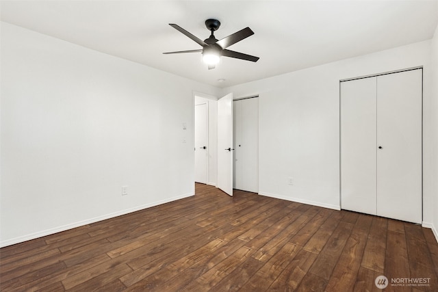 unfurnished bedroom with wood-type flooring, ceiling fan, baseboards, and two closets