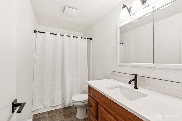 bathroom featuring toilet, stone finish flooring, shower / bath combo with shower curtain, vanity, and backsplash