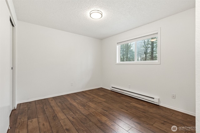 unfurnished room featuring a baseboard heating unit, dark wood-type flooring, a textured ceiling, and baseboards