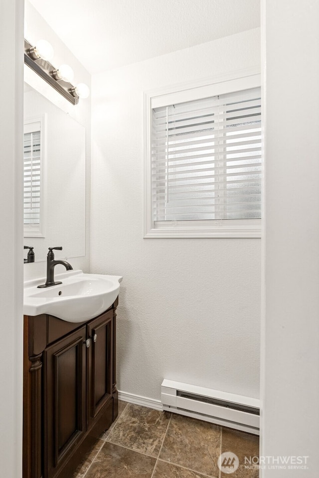 bathroom featuring a baseboard heating unit, vanity, and baseboards