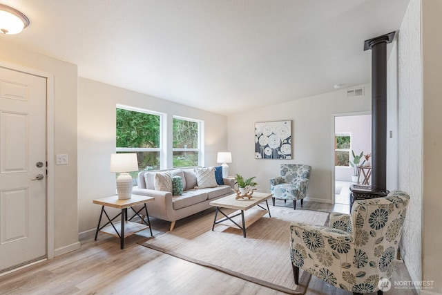 living room with visible vents, vaulted ceiling, light wood-style floors, and a healthy amount of sunlight