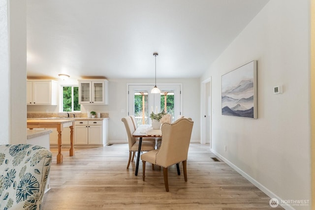 dining space featuring visible vents, light wood-type flooring, and baseboards