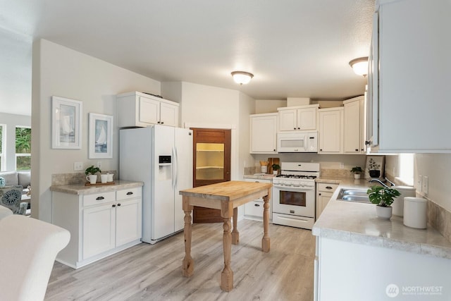 kitchen featuring white appliances, light wood-type flooring, white cabinets, light countertops, and a sink