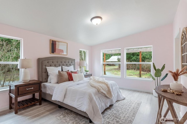 bedroom with light wood finished floors, baseboards, and vaulted ceiling