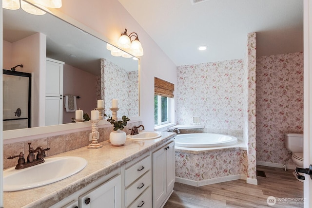 bathroom with a sink, toilet, wood finished floors, and wallpapered walls
