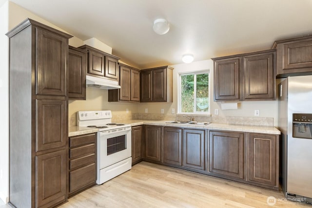 kitchen featuring stainless steel refrigerator with ice dispenser, a sink, light countertops, white range with electric cooktop, and under cabinet range hood