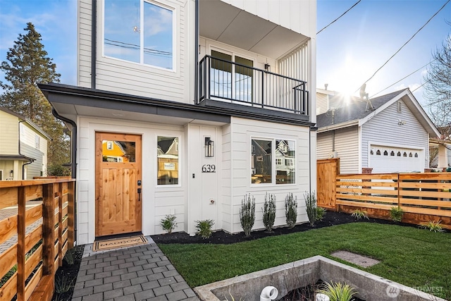 property entrance with a yard, fence, a balcony, and a garage