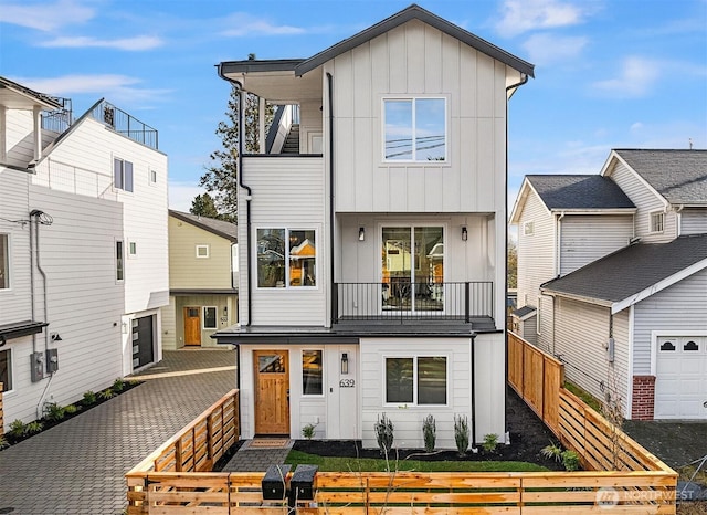 view of front of house featuring board and batten siding, a balcony, and a fenced front yard