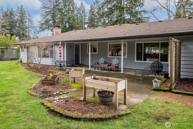 back of property featuring a patio area, a garden, a lawn, and a chimney