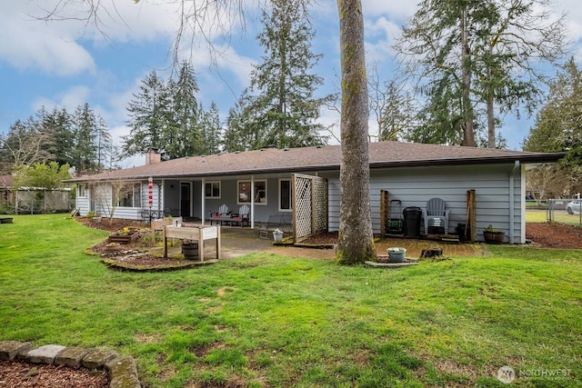 rear view of property with a patio area, a yard, fence, and a chimney