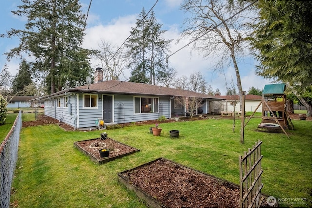 back of property with fence, a playground, a yard, a garden, and a chimney