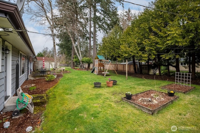 view of yard featuring a playground, a fenced backyard, and a garden