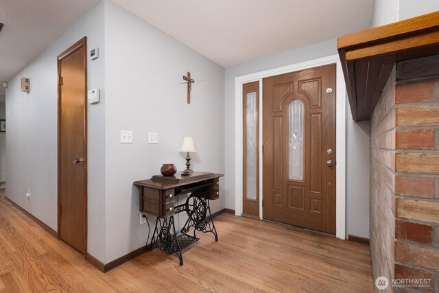 foyer entrance featuring vaulted ceiling, light wood-style flooring, and baseboards