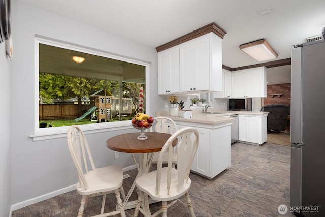 kitchen with stainless steel appliances, a peninsula, white cabinets, and light countertops