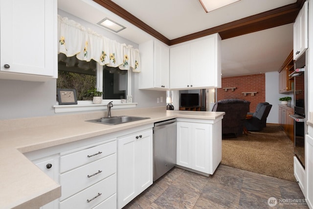 kitchen featuring appliances with stainless steel finishes, white cabinetry, light countertops, and a sink