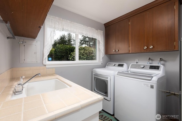 washroom featuring washing machine and dryer, cabinet space, and a sink