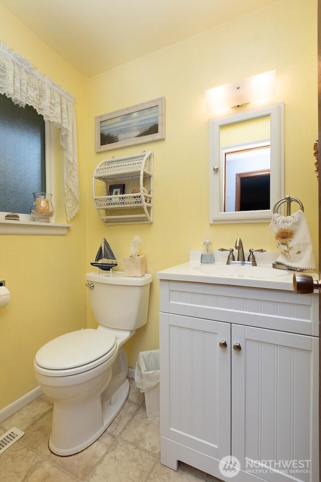 bathroom featuring visible vents, toilet, vanity, and baseboards