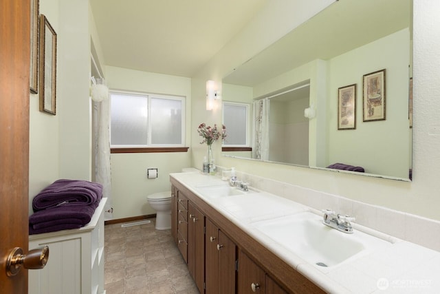 bathroom featuring a sink, toilet, a shower with shower curtain, and double vanity