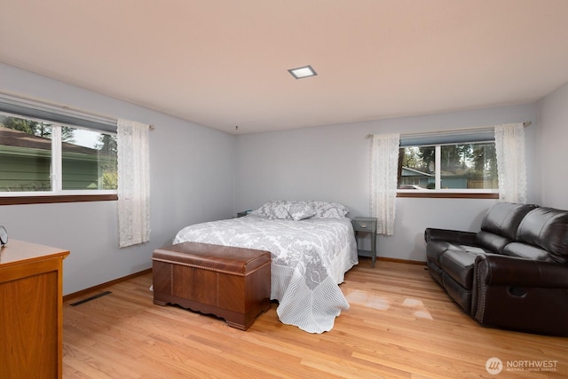 bedroom featuring light wood finished floors, visible vents, and multiple windows