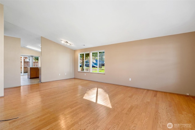 empty room featuring light wood-type flooring and vaulted ceiling