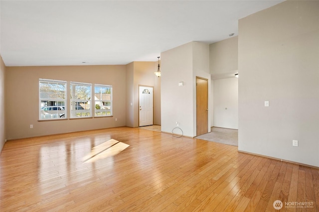 unfurnished living room featuring high vaulted ceiling and light wood-type flooring