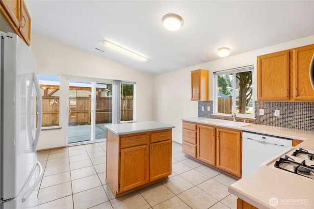 kitchen featuring white appliances, light tile patterned floors, lofted ceiling, and a sink