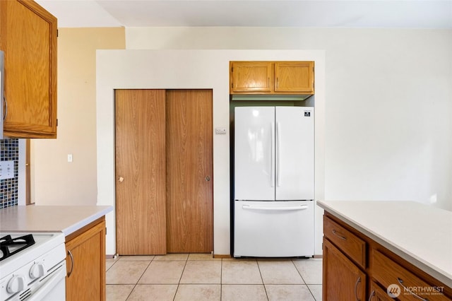 kitchen featuring light tile patterned floors, brown cabinets, light countertops, and freestanding refrigerator