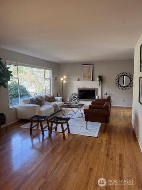 living room with a fireplace, light wood-style flooring, and baseboards