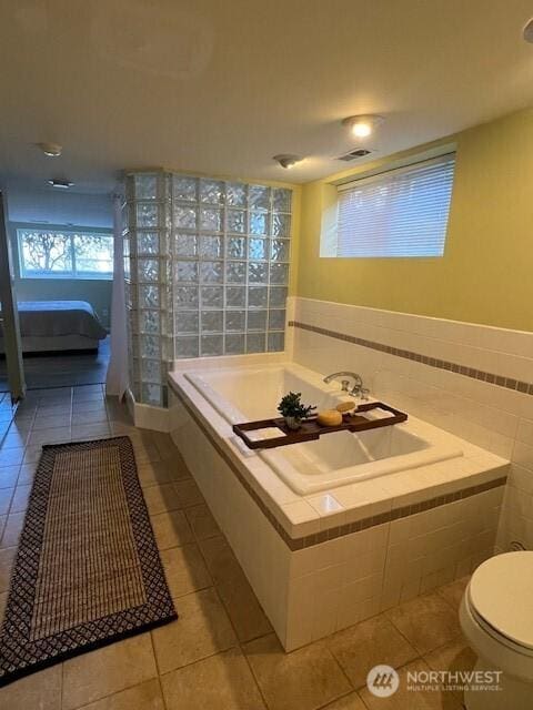 bathroom with toilet, a bath, and tile patterned floors