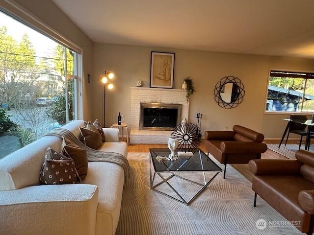 living room featuring a brick fireplace, a wealth of natural light, and wood finished floors