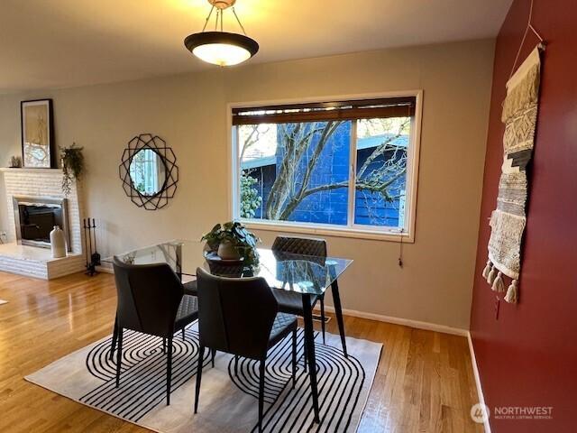 dining area featuring a fireplace, baseboards, and wood finished floors